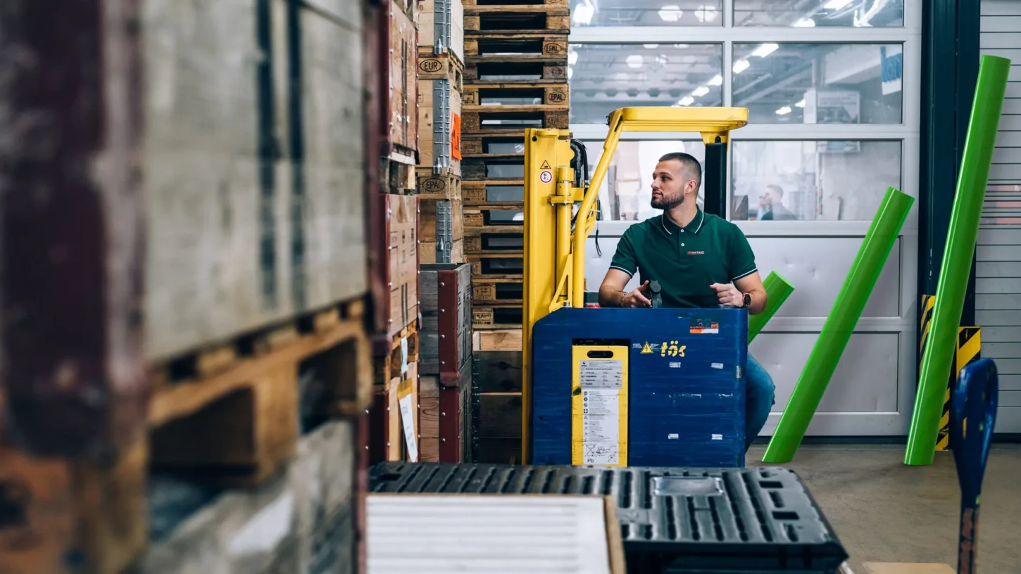 Fachperson in der Logistik arbeitet in einem Lager zwischen Regalen und Waren.