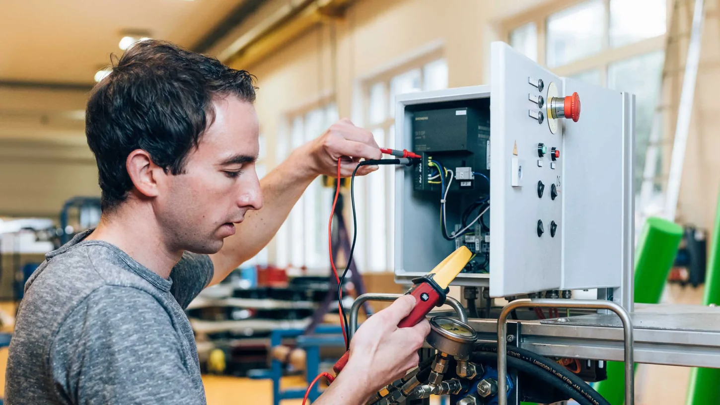 Fachperson für Instandhaltung prüft technische Komponenten an einer Anlage.